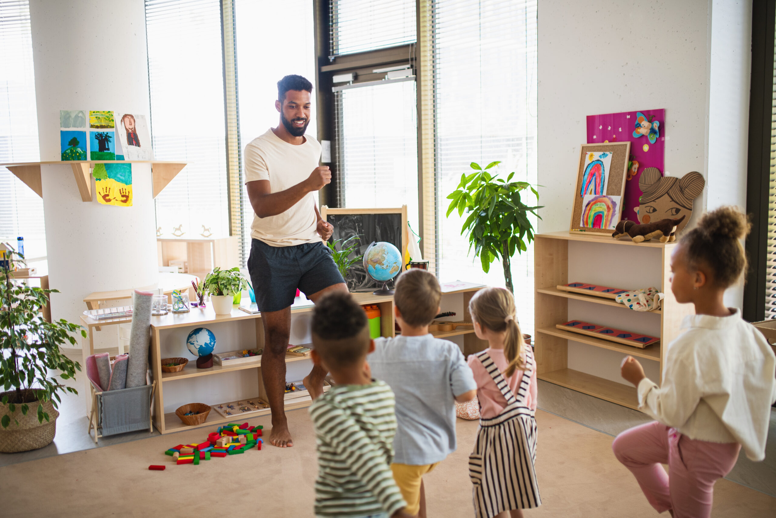 Nursery practitioner leading a group of young children in a classroom activity