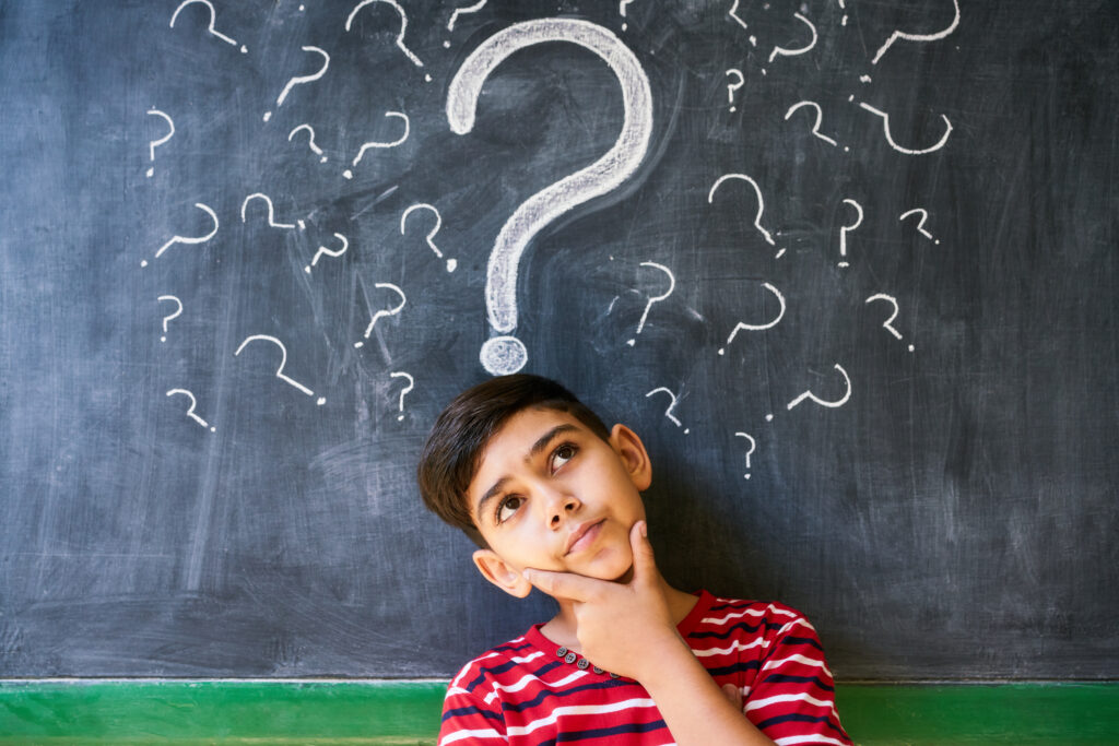 Child thinking with question marks on a blackboard