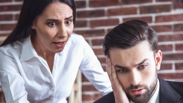Woman confronting an upset colleague at his desk