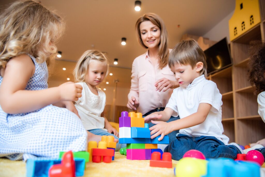 Practitioner and children playing with colourful building blocks