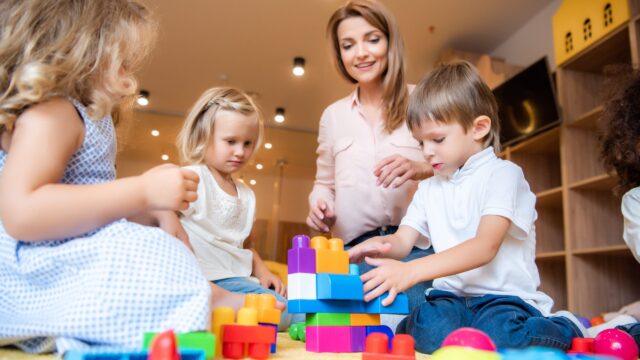 Practitioner and children playing with colourful building blocks