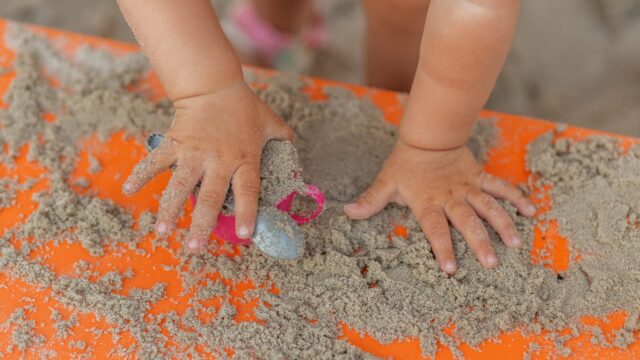 Close-up of a young child's hands playing in sand