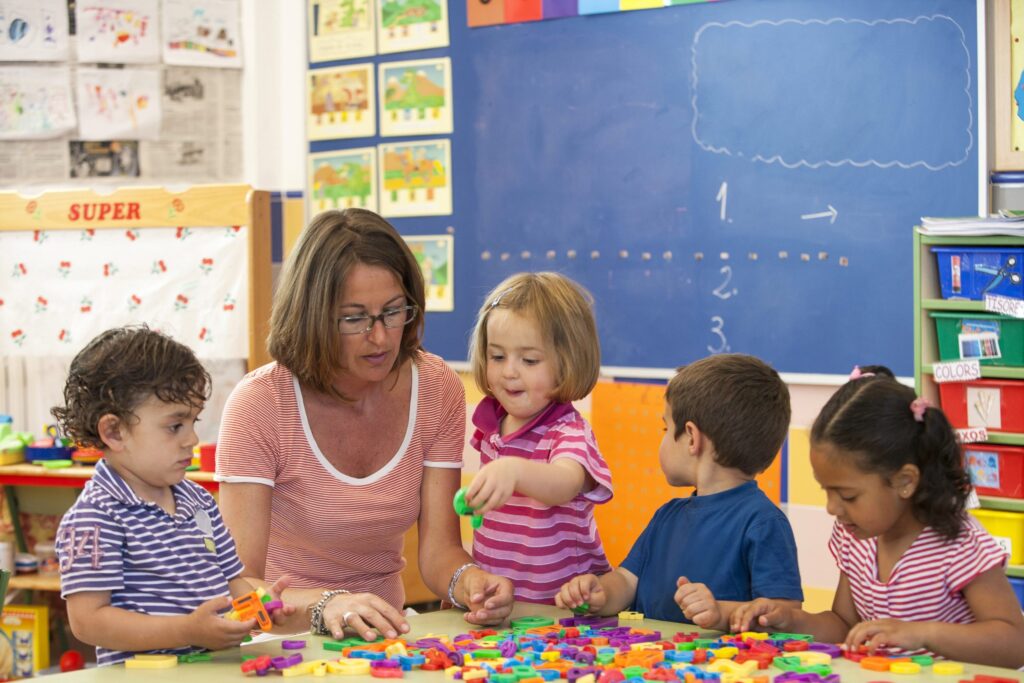 Early years practitioner playing with a group of toddlers