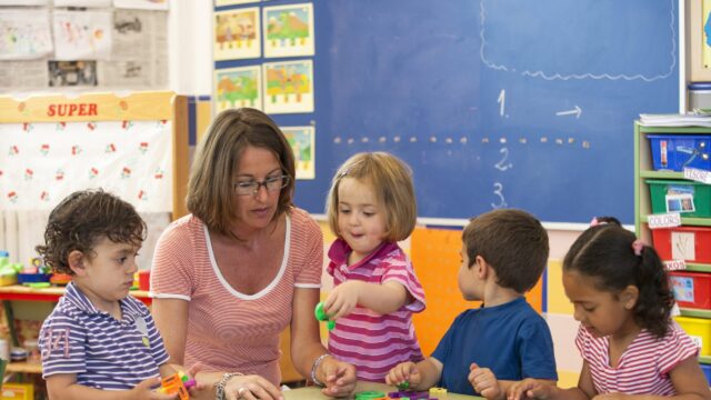 Early years practitioner playing with a group of toddlers