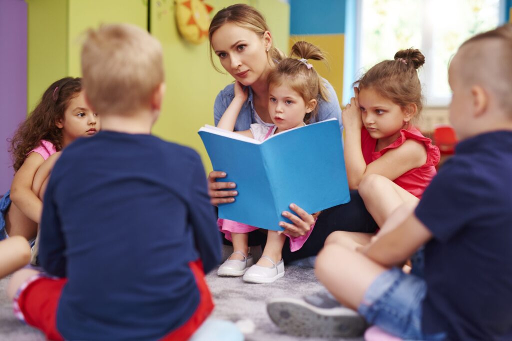 Practitioner reading a picture book to a group of young children