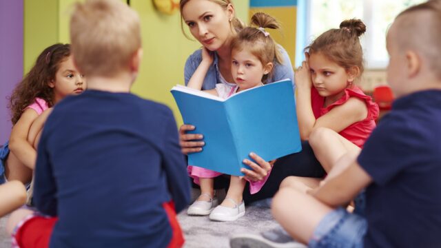 Practitioner reading a picture book to a group of young children